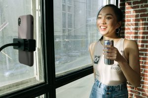 woman holding a can in front of a smartphone